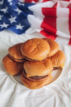 Delicious burgers stacked with an American flag backdrop, perfect for a patriotic celebration.