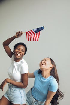 Two women joyfully celebrating with an American flag, symbolizing unity and freedom.