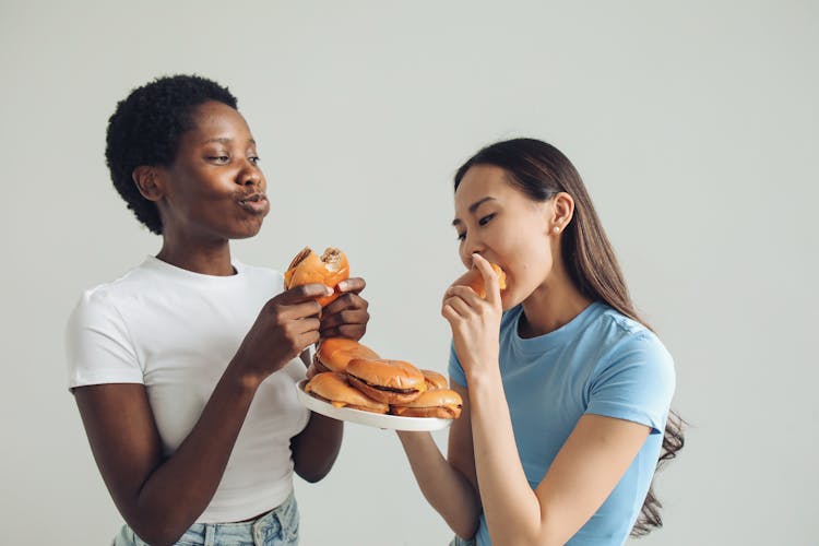 Women In White And Blue Shirts Eating Burgers