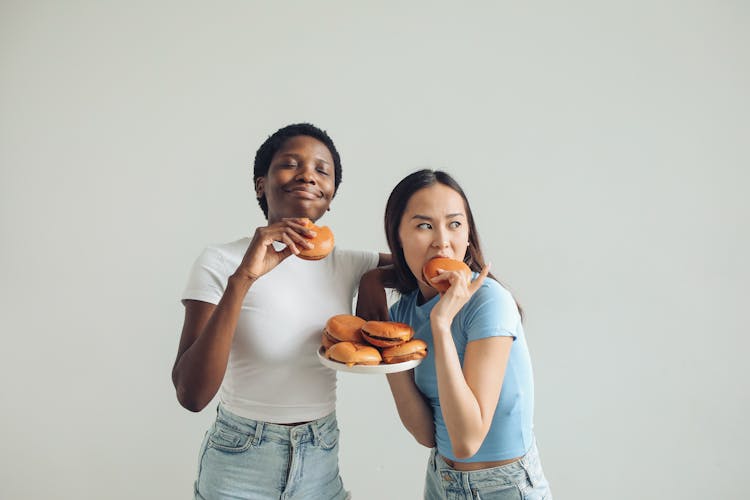 Women In Blue And White Shirts Eating Burgers