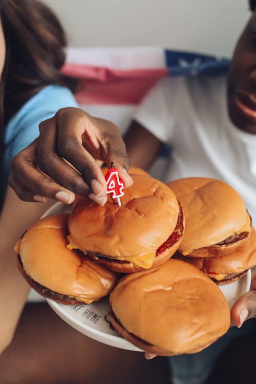 Person in White Shirt Holding a Plate with Burgers