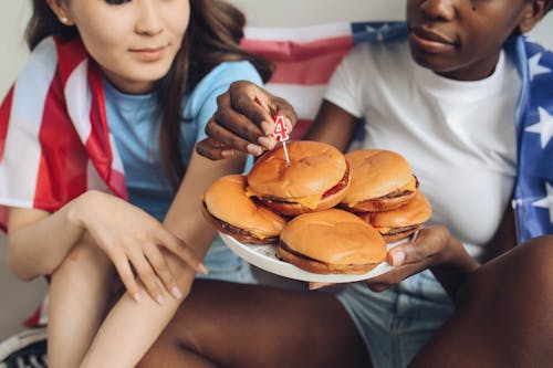 Woman in White Shirt Holding a Plate Burger with Burgers