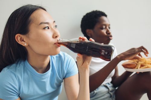 Free Two women enjoying soda and snacks in a relaxed indoor setting, capturing a moment of casual refreshment. Stock Photo