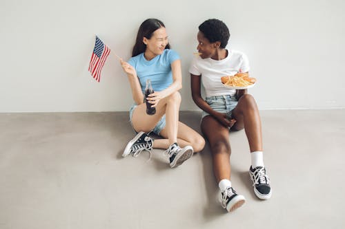 Woman in Blue Shirt Holding a Flag Beside Woman in White Shirt