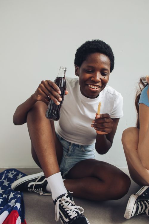Free Joyful woman enjoying Independence Day with a drink and snack indoors. Stock Photo