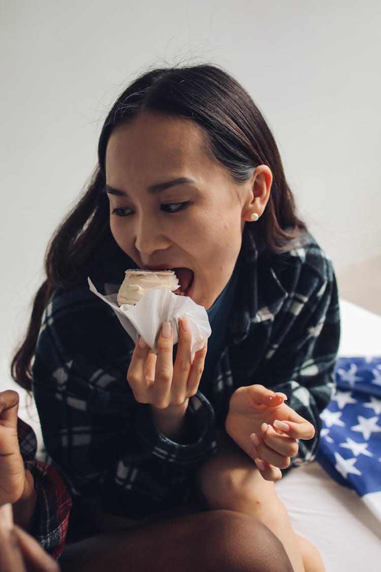 Woman Plaid Long Sleeve Shirt Eating A Cupcake