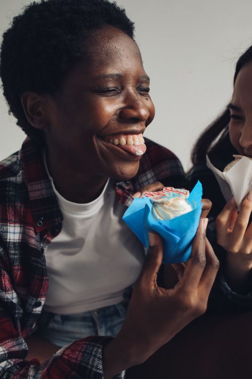 Free Smiling friends savoring delicious cupcakes, capturing a moment of joy and friendship. Stock Photo