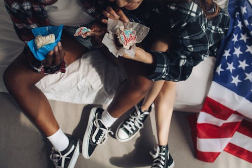 People Sitting on a Bed Holding Cupcakes