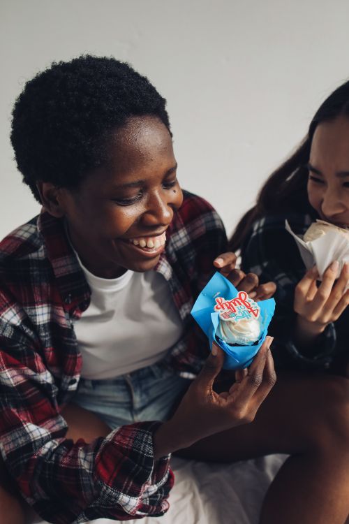 Free Happy friends indulging in delicious cupcakes indoors, sharing laughter and joy together. Stock Photo
