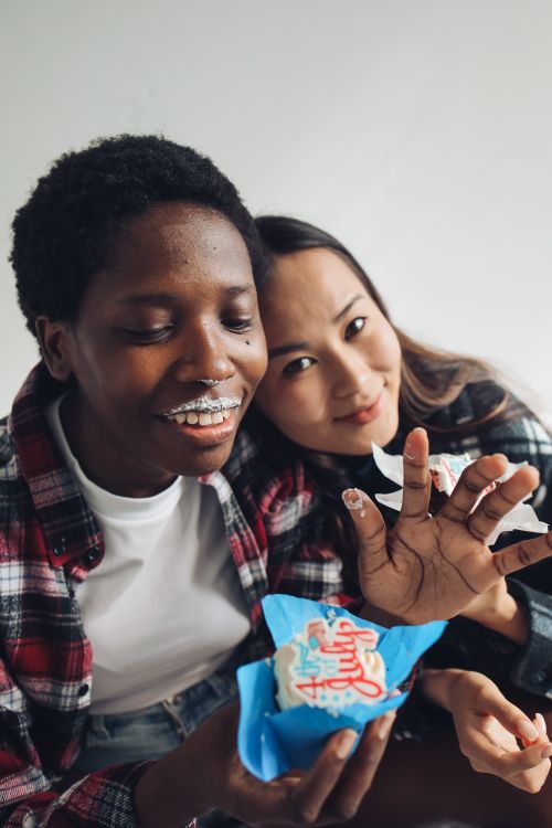 Free Two diverse friends celebrating with 4th of July themed cupcakes in a cheerful indoor setting. Stock Photo