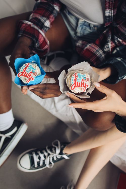 Free Two people enjoying 4th of July cupcakes, celebrating Independence Day with festive desserts. Stock Photo