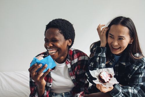 Free Two women laughing and enjoying cupcakes indoors. Capturing happiness and friendship. Stock Photo