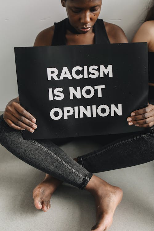 Woman in Black Tank Top Holding a Poster on Racism