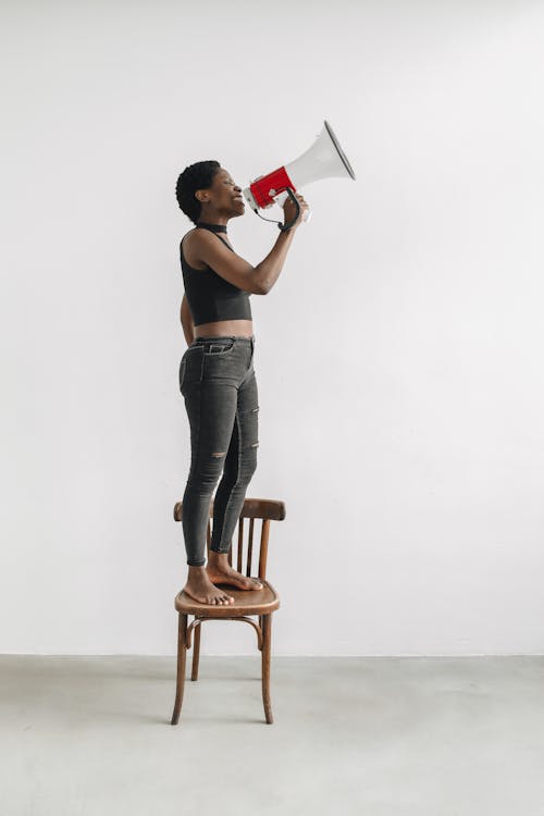 Free Woman Protesting Through a Megaphone While Standing on a Chair Stock Photo