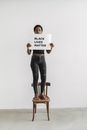 Woman Holding a Signage While Standing on a Chair