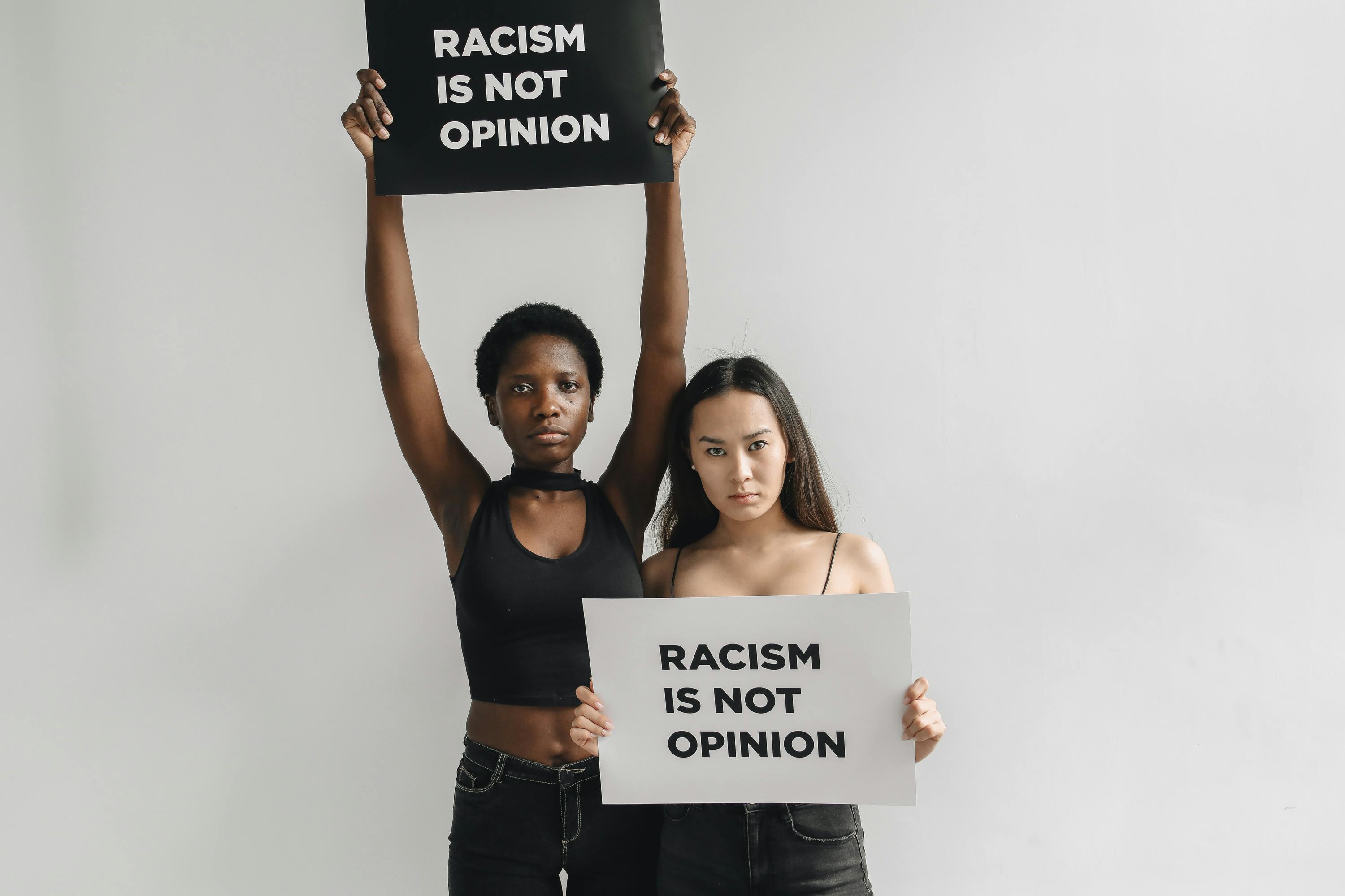 women standing next to each other while holding a placard