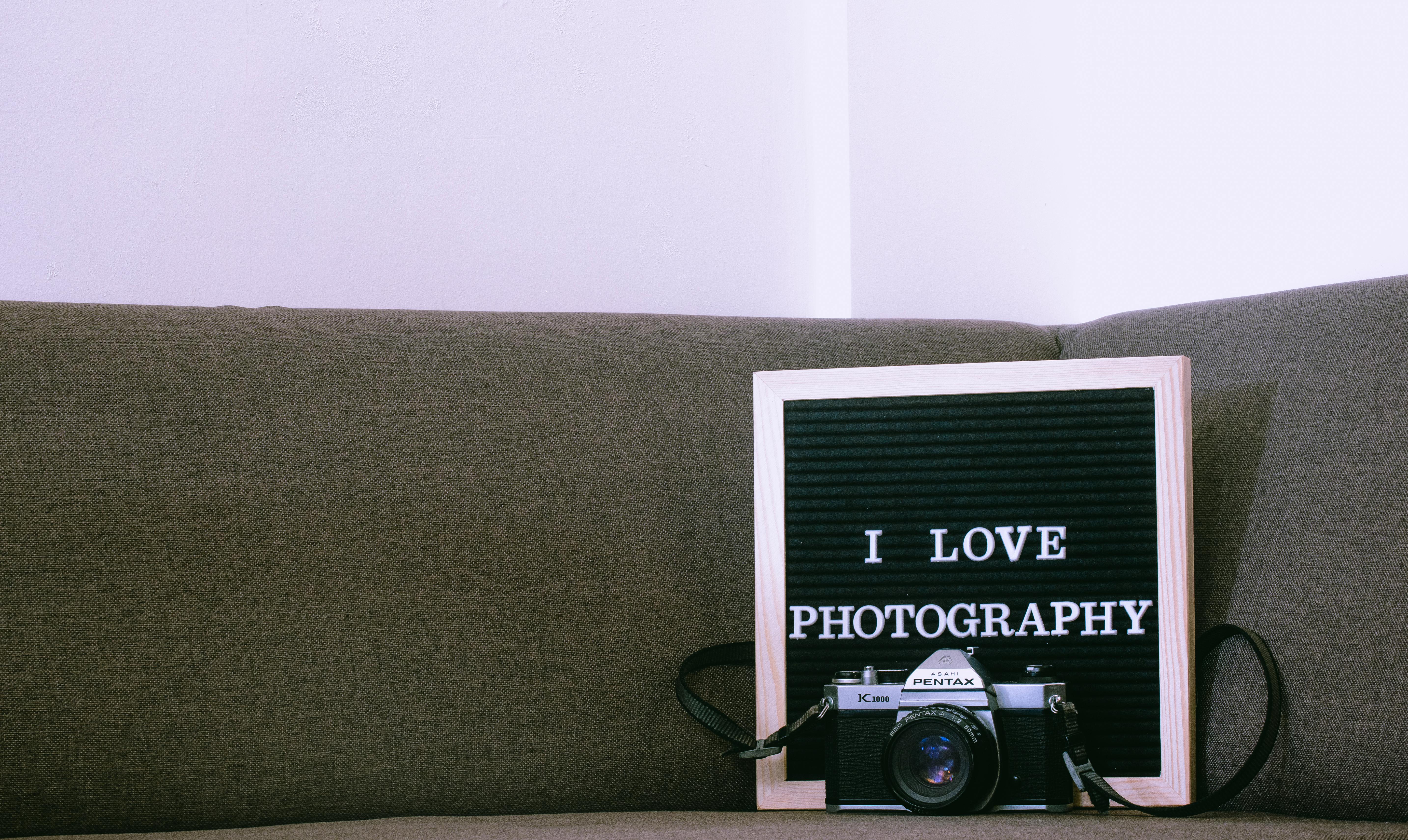 A vintage camera with a letter board displaying 'I Love Photography' on a sofa.