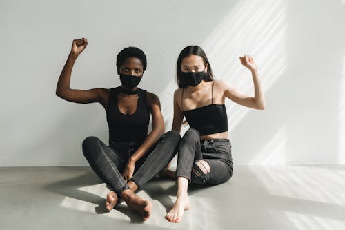 Two Women in Black Clothing Showing Gesture with a Fist