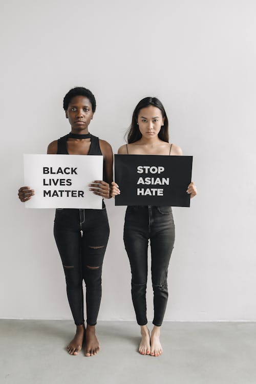 Women Holding White and Black Posters on Racism