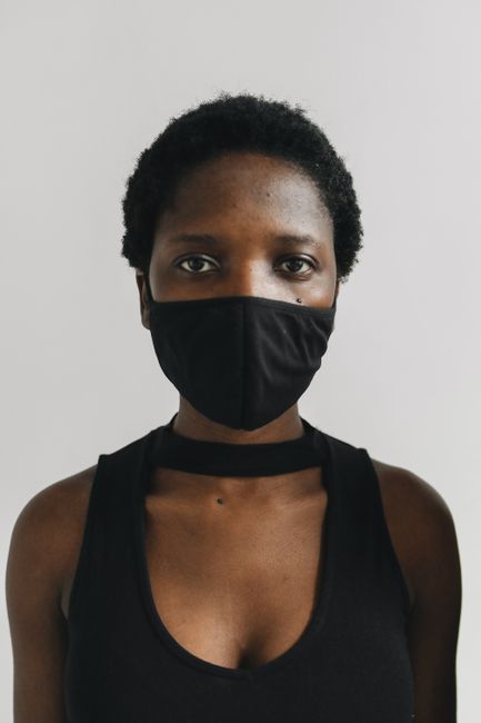 Close-up portrait of a woman with short hair wearing a black face mask.
