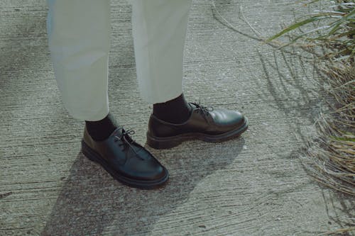 A Person Wearing Black Leather Shoes
