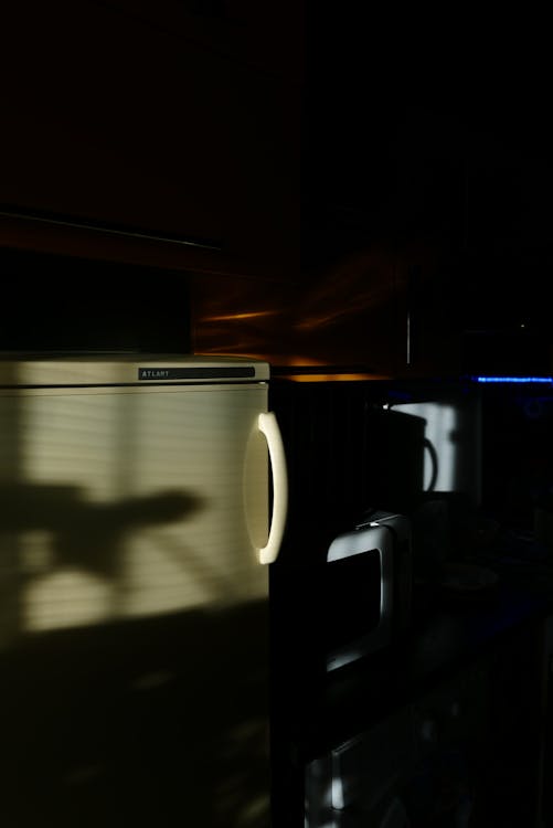 White Microwave Oven Beside the Refrigerator Inside the Dark Room