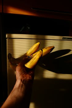 Close-up of ripe bananas held in hand with dramatic shadow play.