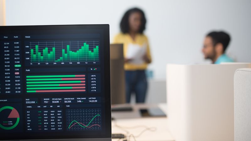 Modern office with financial trading screens and a diverse team discussing strategies.