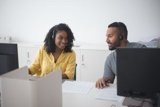 Two call center agents working together with headsets in a modern office environment.