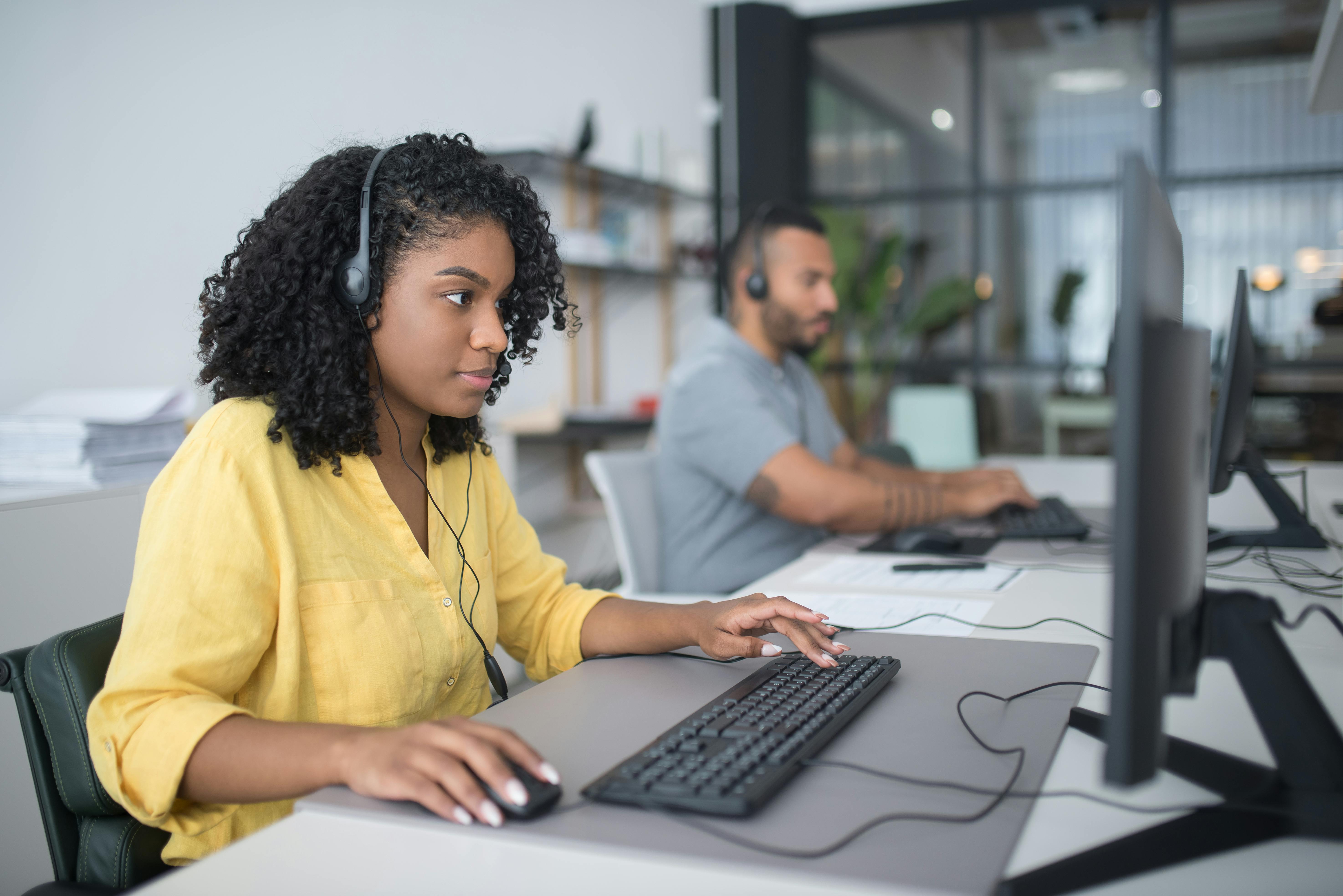 woman in yellow dress shirt using computer