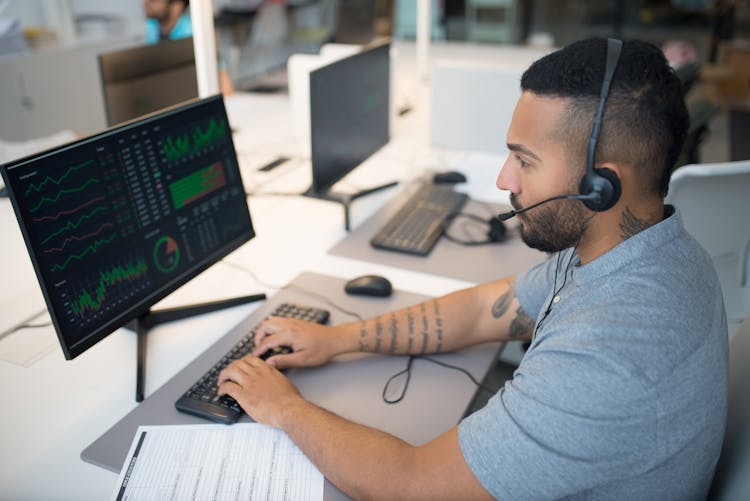 Man In Gray Shirt Working On A Desktop Computer