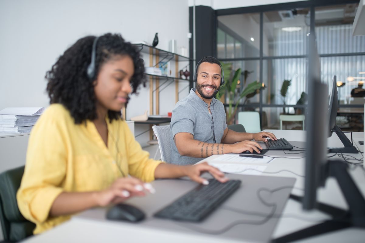 Two call-centre agents with headsets working at their computers