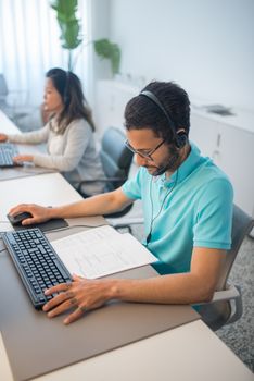 Two professionals working in a modern office setting, focusing on documents and computers, fostering productivity.