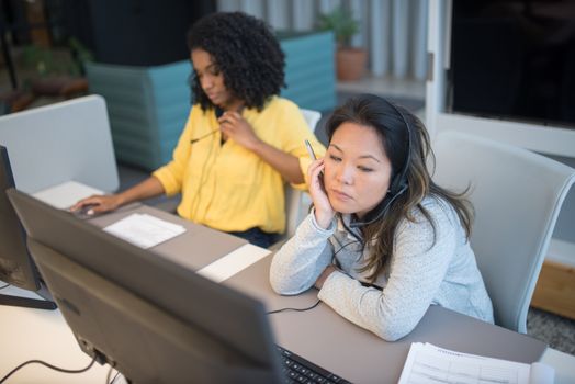 Two women focused on work in a modern call center office environment.