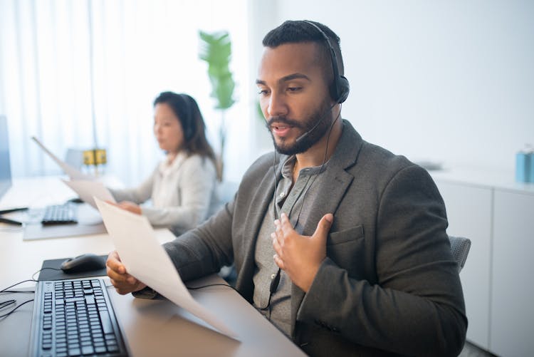 Man In Gray Blazer Wearing Headset While Working In The Office