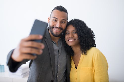 Man and Woman Taking Photo of Themselves using a Cellphone