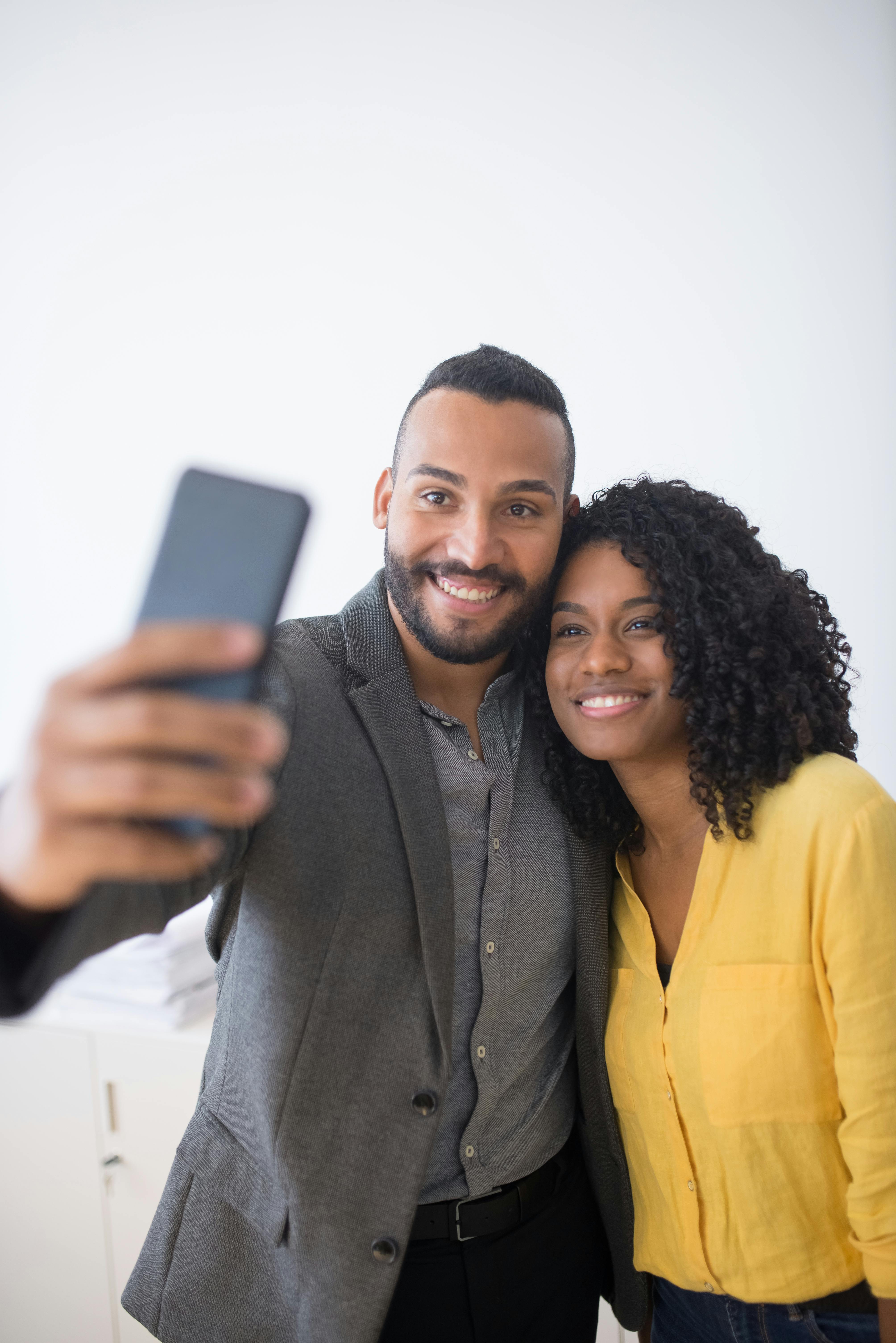 man and woman taking photo of themselves using a cellphone