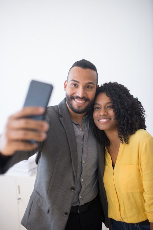 Man and Woman Taking Photo of Themselves using a Cellphone