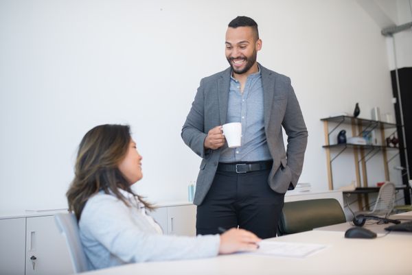 Two coworkers talking over coffee at a desk — photo by Kampus Production on Pexels