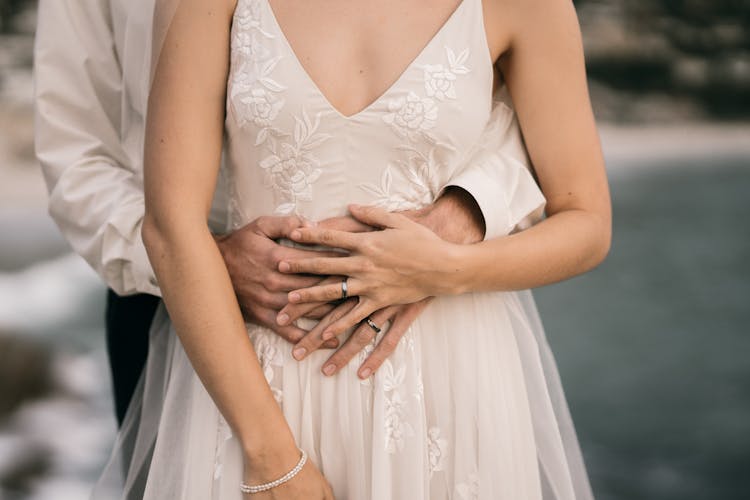 Man In White Dress Shirt Hugging Woman In White Sleeveless Wedding Dress