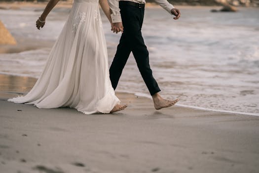 A couple walks barefoot along the seashore, celebrating their wedding day with love and tranquility.