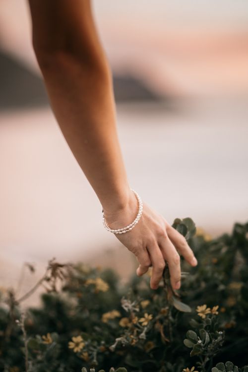 Free Elegant hand with bracelet gently touches plants, showcasing nature's connection. Stock Photo