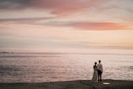 日落时分，一对夫妇在岩石海边拥抱，营造出浪漫而宁静的氛围