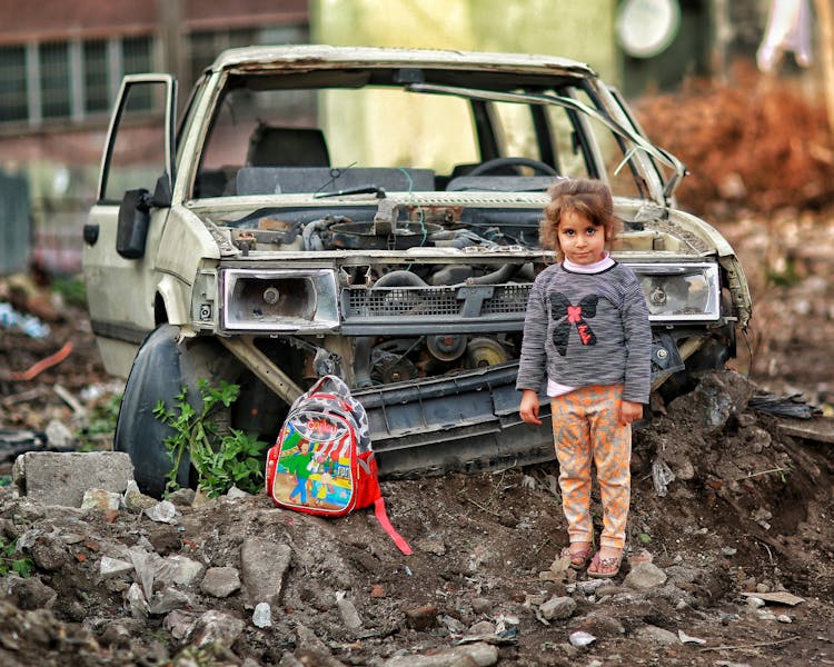 Girl With Backpack Near Broken Car Ruins