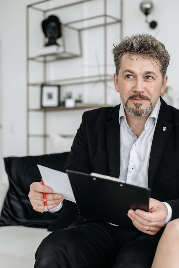 Man In Black Suit Holding Black Clipboard