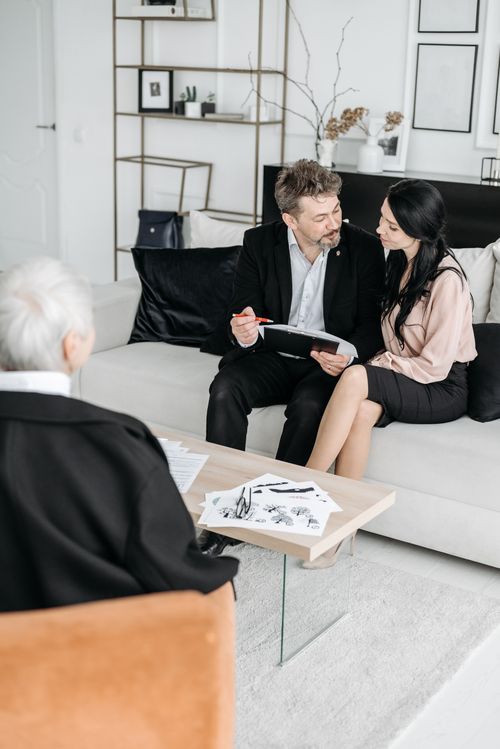 Free A mature couple sits with an advisor on a couch, discussing documents in a modern office. Stock Photo