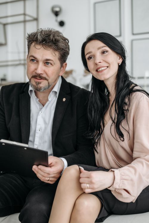 Free Smiling couple sitting together indoors, looking at documents, conveying warmth and togetherness. Stock Photo