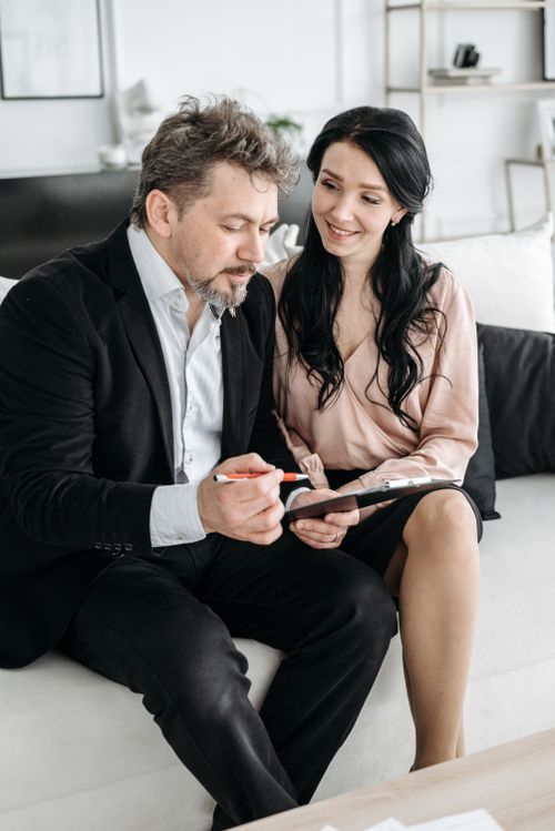Free A couple sitting together on a couch, reviewing important documents indoors. Stock Photo