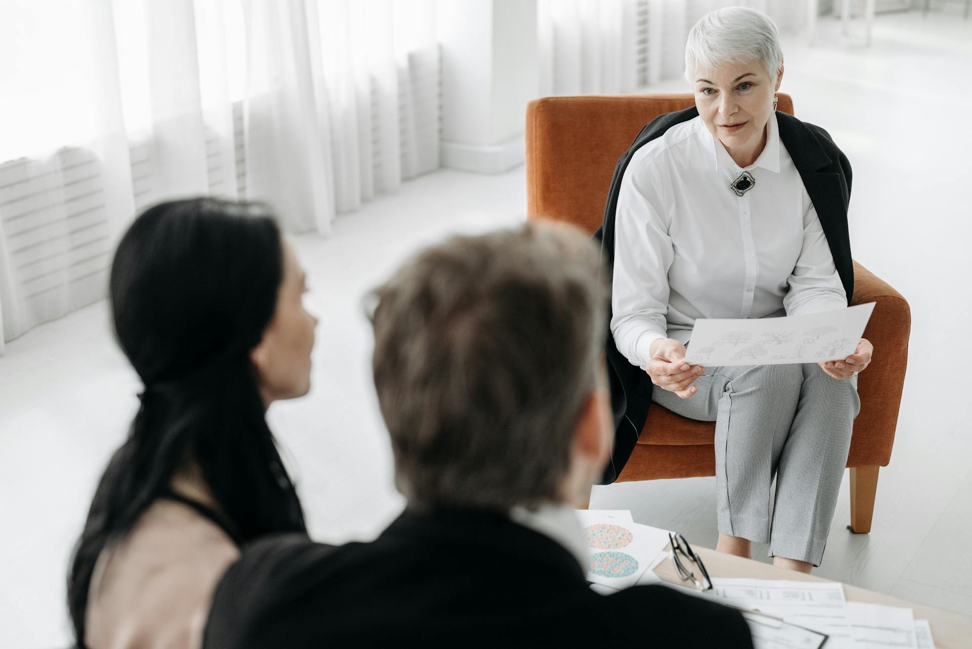 Professional advisor discussing documents with a couple in a modern office setting.