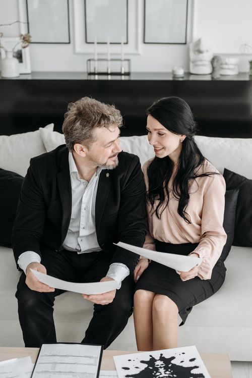 Free Smiling couple reviewing business documents on a sofa, showcasing teamwork and collaboration. Stock Photo